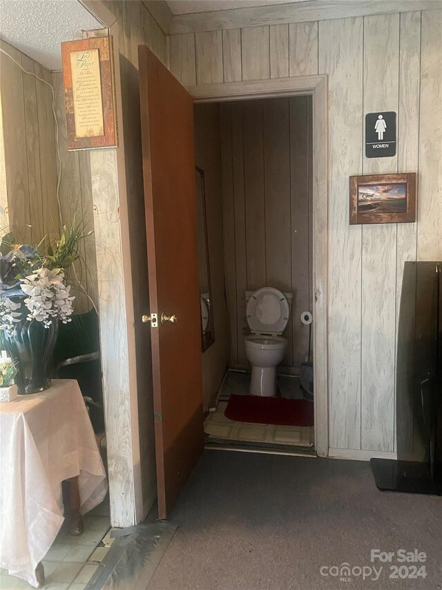 bathroom with wood walls and toilet