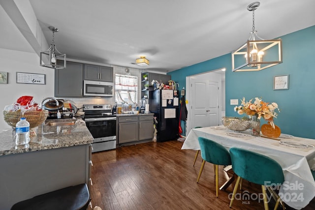 kitchen with gray cabinets, an inviting chandelier, stainless steel appliances, and dark hardwood / wood-style flooring