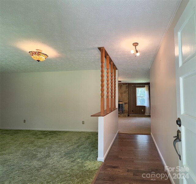 corridor featuring a textured ceiling and dark colored carpet