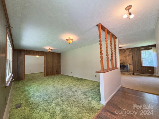 interior space with a textured ceiling, carpet, wooden walls, and a fireplace