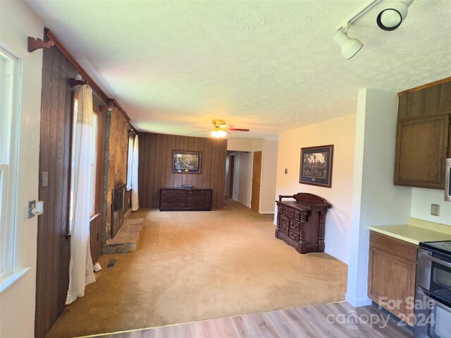 carpeted living room with a textured ceiling, wood walls, and ceiling fan