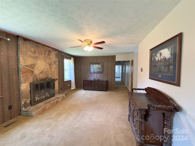 unfurnished living room with carpet flooring, a fireplace, a textured ceiling, and ceiling fan