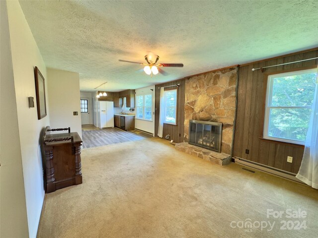 living room with a textured ceiling, a stone fireplace, ceiling fan, and carpet