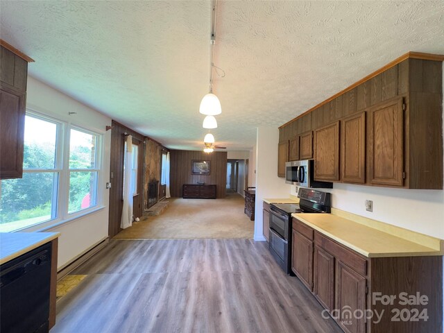 kitchen featuring hanging light fixtures, light colored carpet, black appliances, ceiling fan, and a textured ceiling