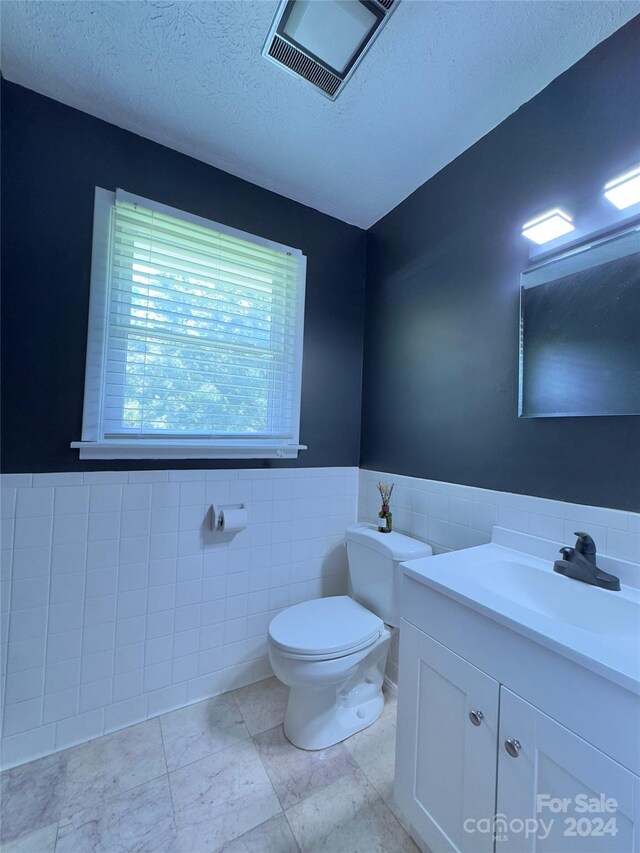 bathroom with vanity, backsplash, tile walls, toilet, and tile patterned floors