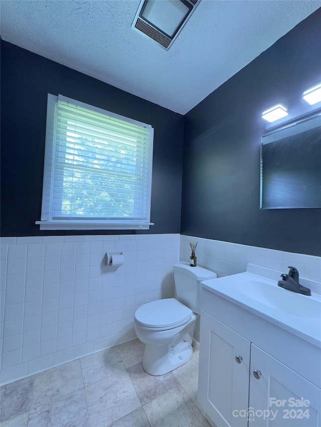 bathroom with toilet, a textured ceiling, vanity, and visible vents