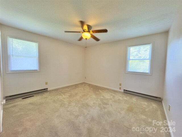 carpeted empty room with plenty of natural light, baseboard heating, and ceiling fan