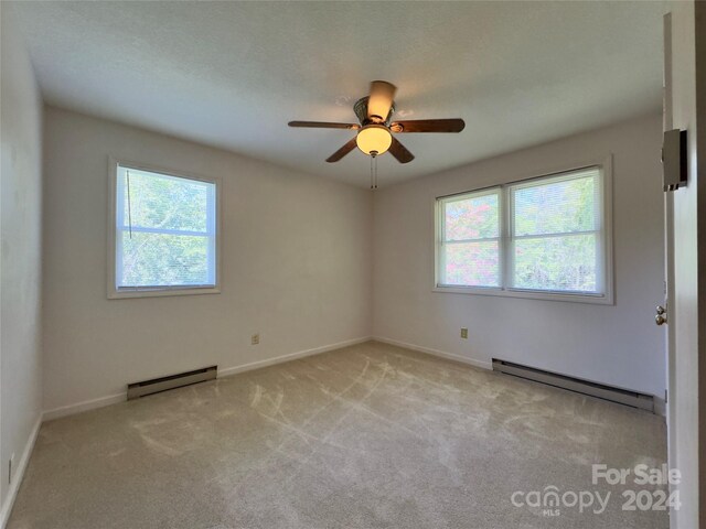 carpeted empty room featuring ceiling fan and baseboard heating