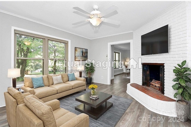 living room with crown molding, dark wood-type flooring, ceiling fan, and a brick fireplace