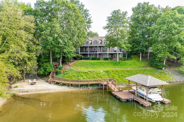 dock area featuring a water view, an outdoor fire pit, and a yard