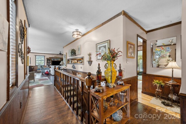 hallway featuring a textured ceiling, hardwood / wood-style floors, and ornamental molding