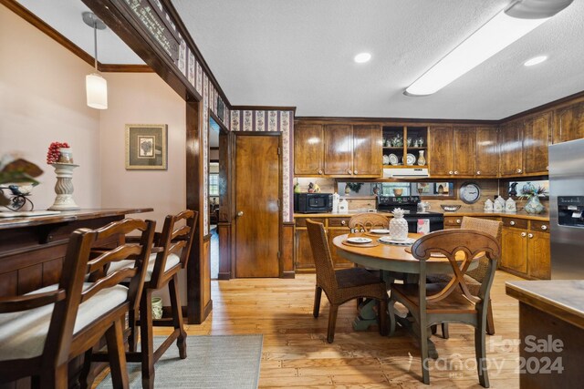 dining space featuring a textured ceiling, crown molding, and light wood-type flooring