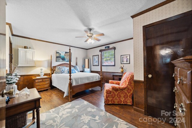 bedroom featuring ceiling fan, a textured ceiling, dark wood-type flooring, and ornamental molding