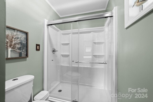 bathroom with crown molding, toilet, and an enclosed shower