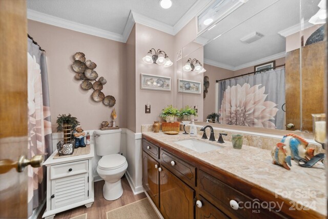 bathroom featuring toilet, ornamental molding, vanity, and hardwood / wood-style flooring