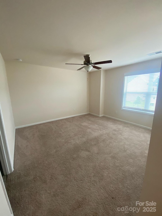 carpeted empty room featuring a ceiling fan, visible vents, and baseboards