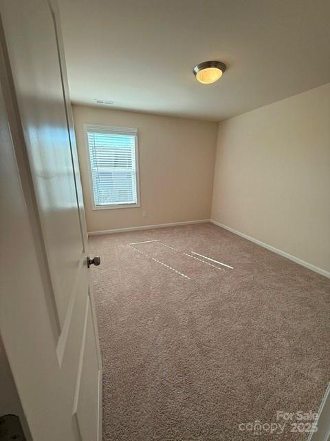 unfurnished room with carpet flooring and baseboards