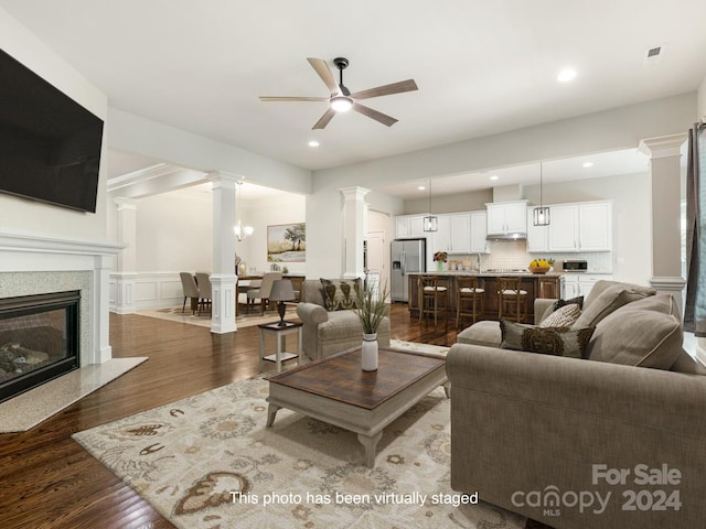 living room featuring ceiling fan, decorative columns, and hardwood / wood-style flooring