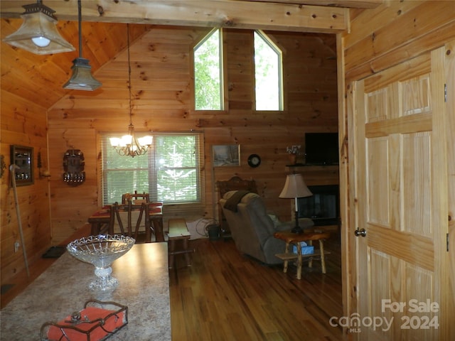 living room featuring vaulted ceiling, wood walls, an inviting chandelier, and wood-type flooring