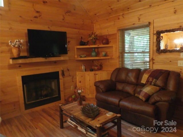 living room with wood walls, vaulted ceiling, and hardwood / wood-style flooring