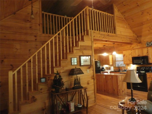 stairs featuring high vaulted ceiling, wood walls, and wood-type flooring