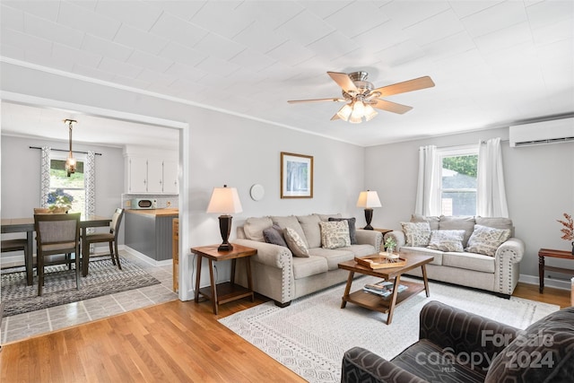 living area featuring ceiling fan, light wood finished floors, a wall unit AC, and crown molding