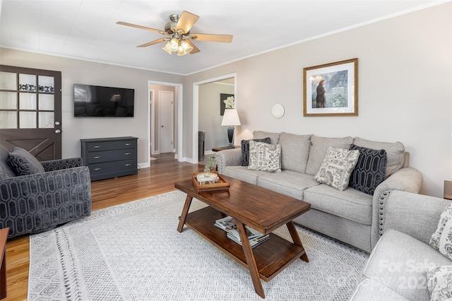 living area with crown molding, baseboards, ceiling fan, and wood finished floors