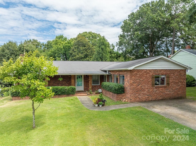 single story home featuring concrete driveway, brick siding, and a front lawn