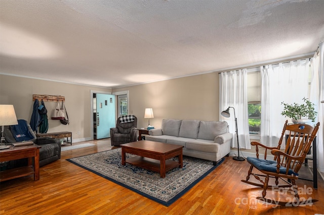 living room featuring crown molding, a textured ceiling, and wood finished floors