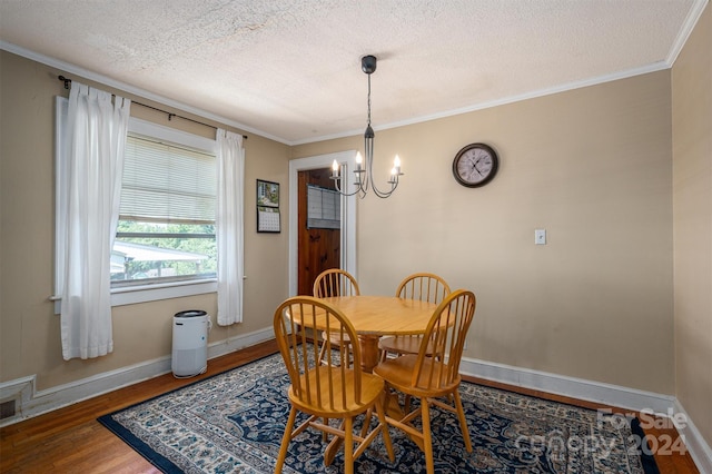 dining room with a textured ceiling, a notable chandelier, wood finished floors, baseboards, and crown molding