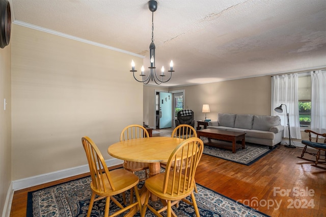 dining space featuring crown molding, baseboards, wood finished floors, and an inviting chandelier