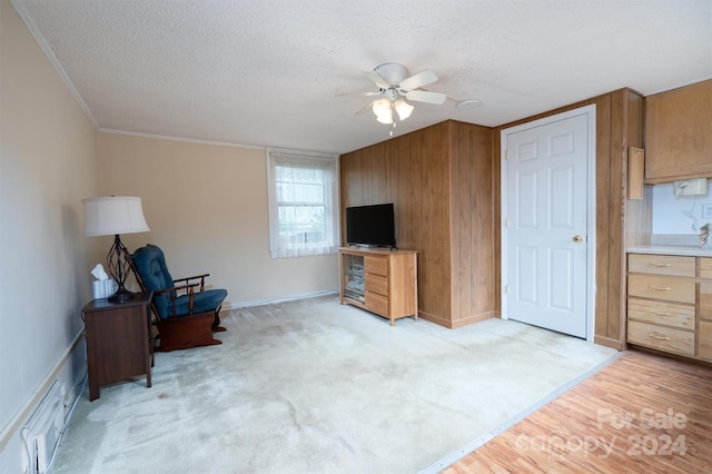 living area with crown molding, light carpet, ceiling fan, a textured ceiling, and baseboards