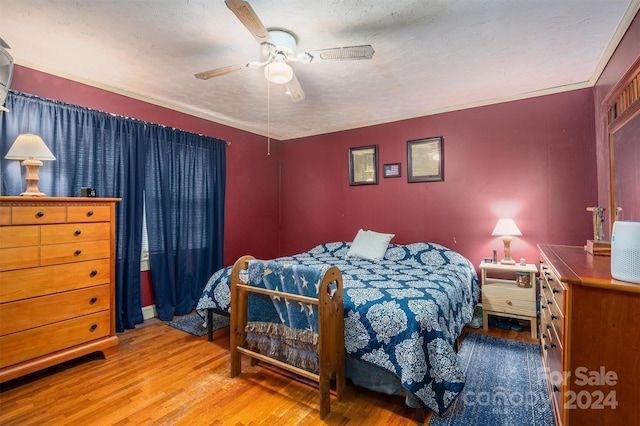 bedroom with a ceiling fan, ornamental molding, a textured ceiling, and wood finished floors