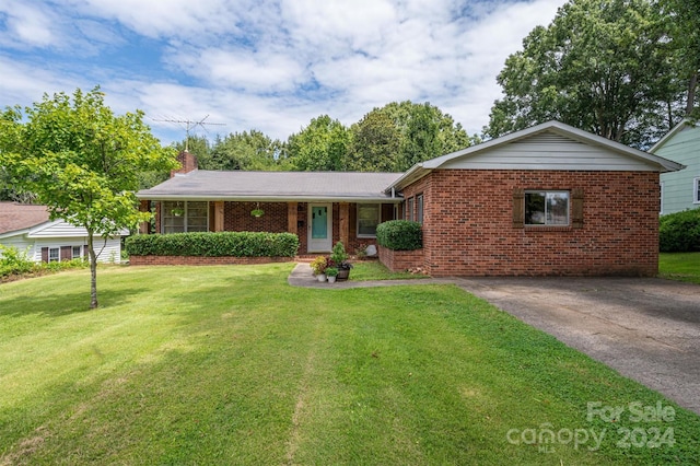 ranch-style home featuring a front yard, a chimney, and brick siding