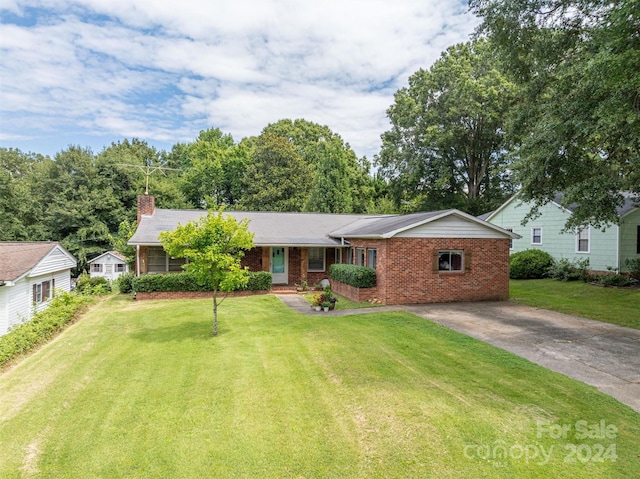 ranch-style home with concrete driveway, brick siding, a chimney, and a front lawn