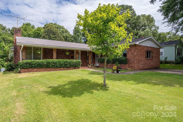 ranch-style home featuring a front lawn, a chimney, and brick siding