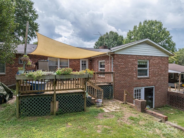 back of property featuring brick siding, a yard, and a deck