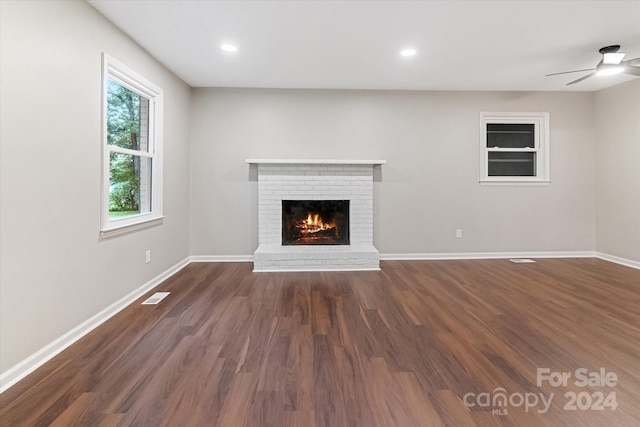 unfurnished living room featuring ceiling fan, a fireplace, and dark wood-type flooring