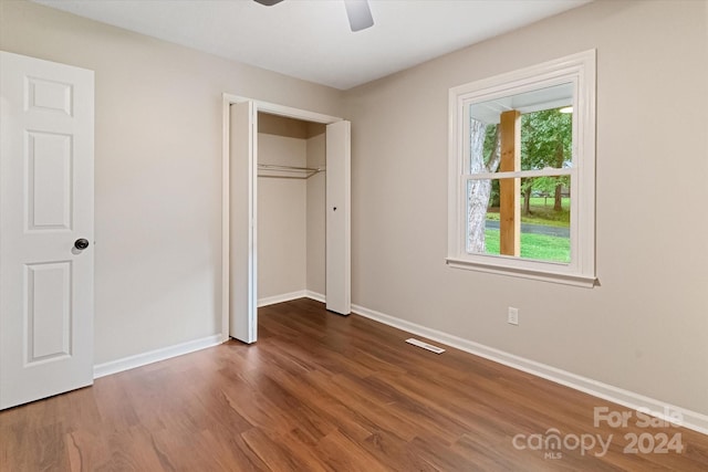 unfurnished bedroom featuring a closet, hardwood / wood-style floors, and multiple windows