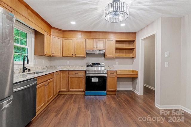 kitchen with sink, an inviting chandelier, appliances with stainless steel finishes, light stone countertops, and dark hardwood / wood-style floors