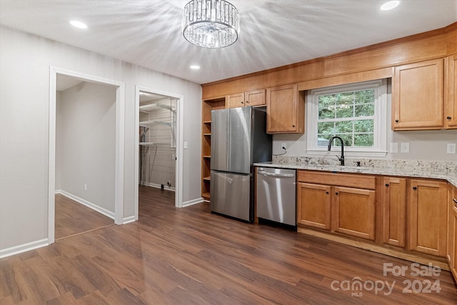 kitchen with sink, stainless steel appliances, light stone counters, and dark hardwood / wood-style flooring