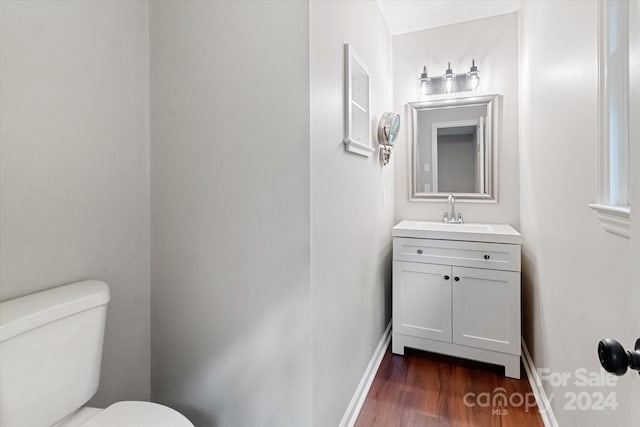 bathroom with hardwood / wood-style floors, toilet, and vanity