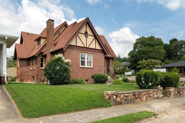 view of side of property featuring brick siding, a lawn, a chimney, crawl space, and stucco siding