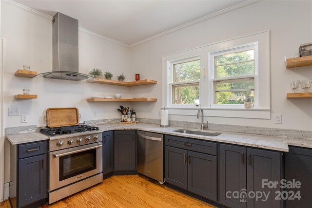 kitchen featuring light wood-type flooring, appliances with stainless steel finishes, light stone countertops, sink, and wall chimney exhaust hood