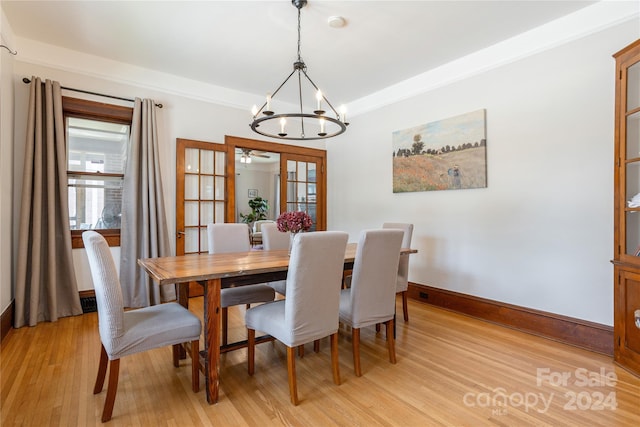 dining room with light wood-type flooring, a chandelier, and crown molding