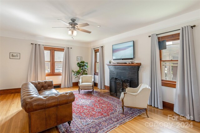 living room with ceiling fan, hardwood / wood-style flooring, a fireplace, and crown molding