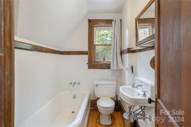 bathroom featuring a bath, toilet, hardwood / wood-style flooring, and vaulted ceiling