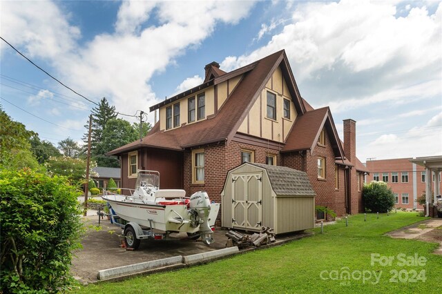 back of property with a yard and a storage unit