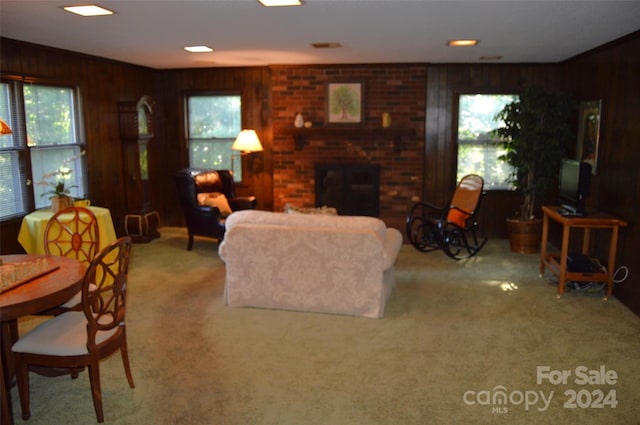 living room with wood walls, carpet flooring, and a brick fireplace