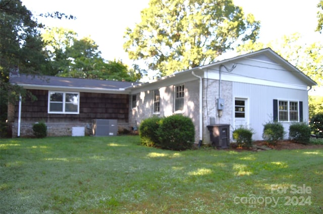 ranch-style home with a front lawn and cooling unit